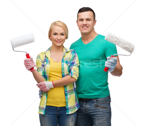 Stock photo: smiling couple in gloves with paint rollers