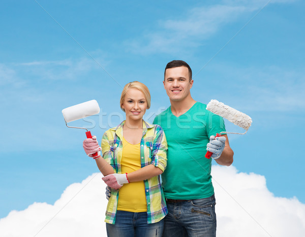 smiling couple in gloves with paint rollers Stock photo © dolgachov
