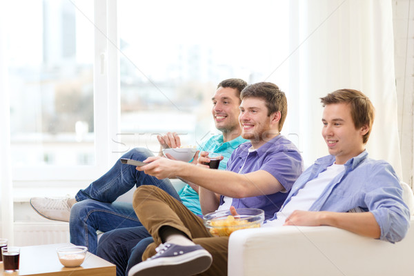 smiling friends with remote control at home Stock photo © dolgachov