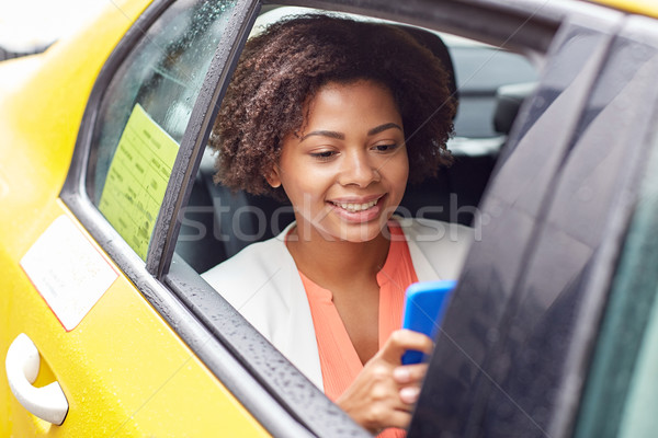 Stock photo: happy african woman texing on smartphone in taxi