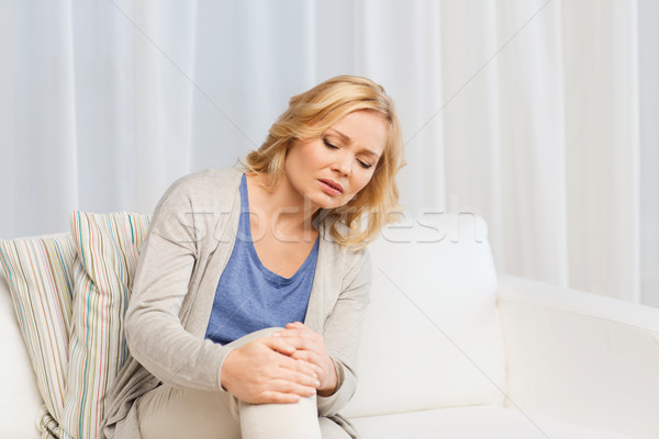 unhappy woman suffering from pain in leg at home Stock photo © dolgachov