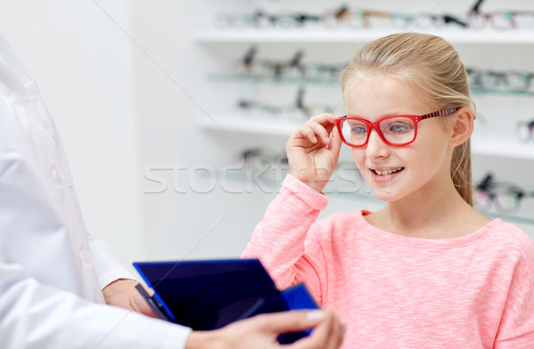 optician and girl choosing glasses at optics store Stock photo © dolgachov