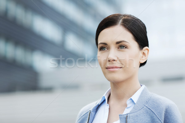 young smiling businesswoman over office building Stock photo © dolgachov