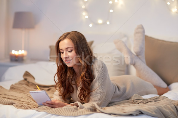 happy young woman with notebook in bed at home Stock photo © dolgachov