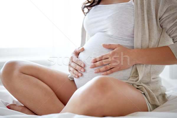 Stock photo: close up of pregnant woman sitting in bed at home