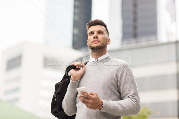young man with smartphone and bag in city Stock photo © dolgachov