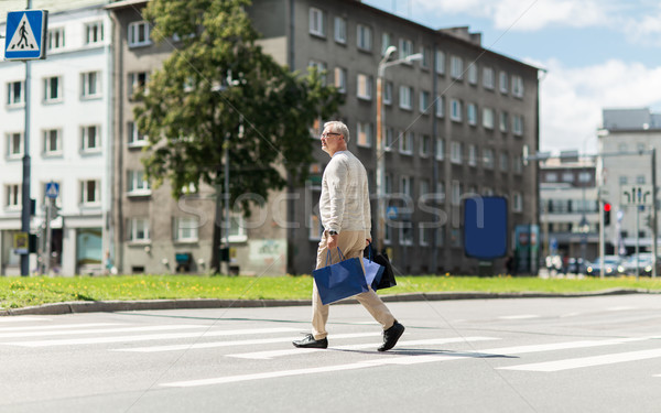 senior man with shopping bags walking on crosswalk Stock photo © dolgachov