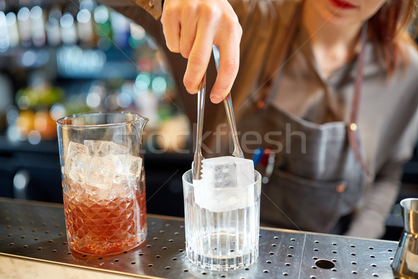 bartender adding ice cube into glass at bar Stock photo © dolgachov