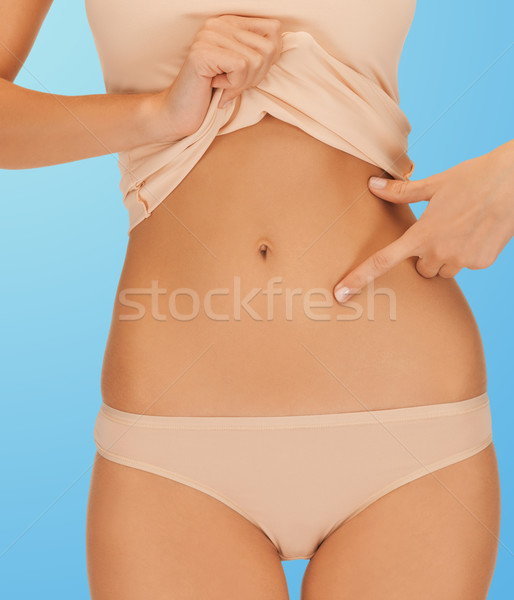 woman pointing at her abs Stock photo © dolgachov