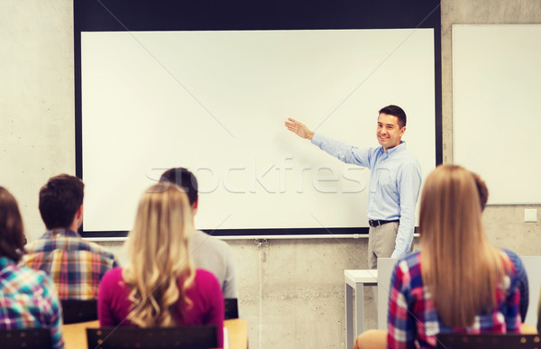 group of students and smiling teacher in classroom Stock photo © dolgachov