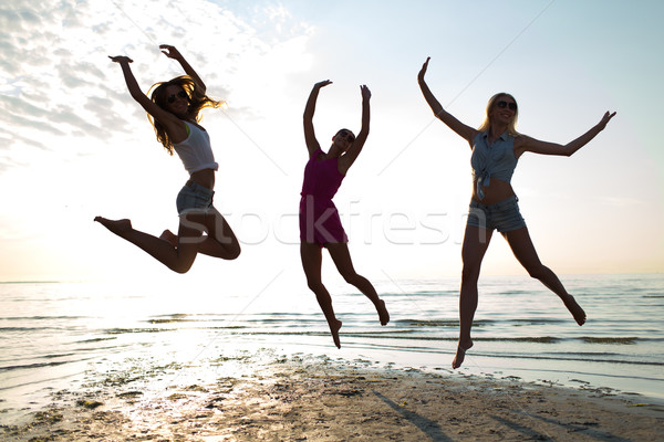 happy female friends dancing and jumping on beach Stock photo © dolgachov