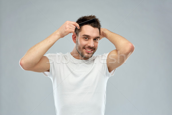 Stock photo: happy man brushing hair with comb over gray