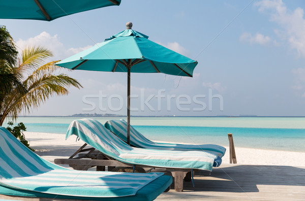 parasol and sunbeds by sea on maldives beach Stock photo © dolgachov