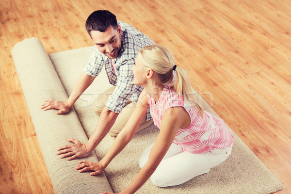 happy couple unrolling carpet or rug at home Stock photo © dolgachov