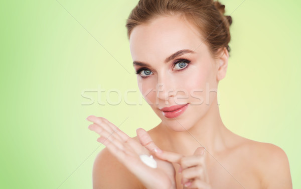 happy young woman with moisturizing cream on hand Stock photo © dolgachov