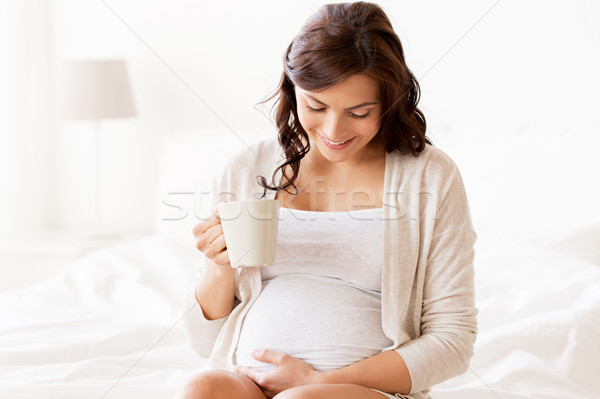 Stock photo: happy pregnant woman with cup drinking tea at home