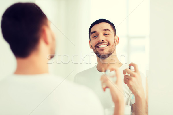 man with perfume looking to mirror at bathroom Stock photo © dolgachov