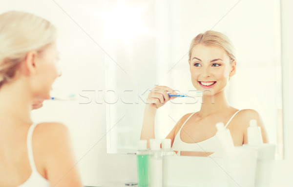 woman with toothbrush cleaning teeth at bathroom Stock photo © dolgachov