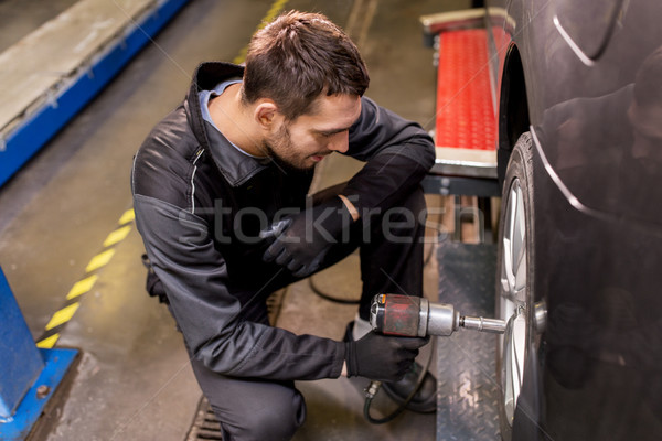auto mechanic with screwdriver changing car tire Stock photo © dolgachov