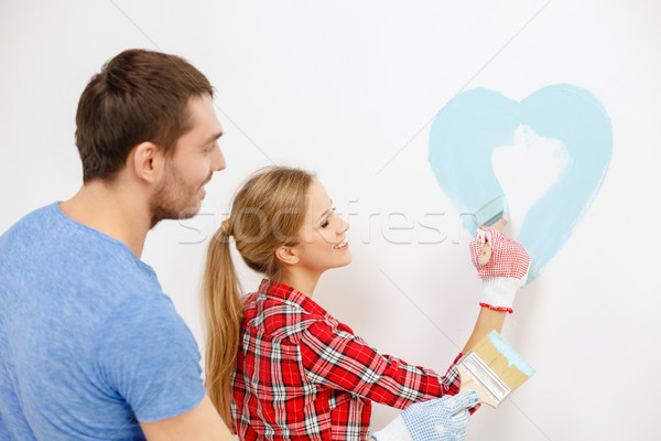 Stock photo: smiling couple painting small heart on wall