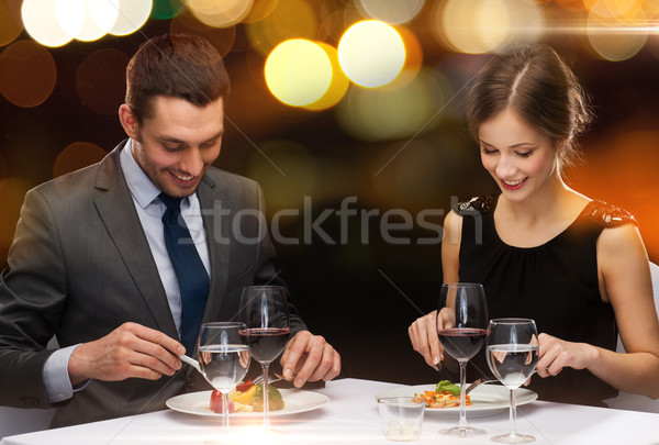 smiling couple eating main course at restaurant Stock photo © dolgachov