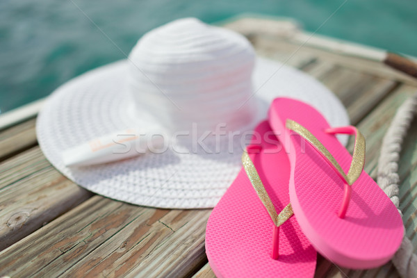 close up of hat, sunscreen and slippers at seaside Stock photo © dolgachov