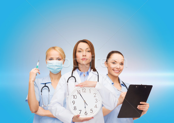 calm female doctor and nurses with wall clock Stock photo © dolgachov