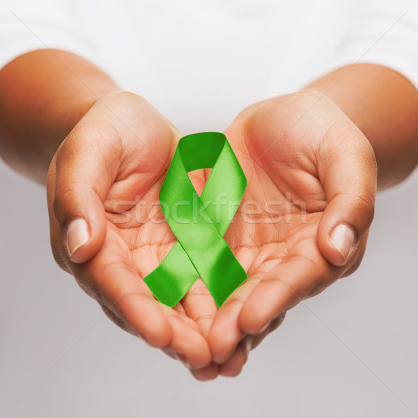 hands holding green awareness ribbon Stock photo © dolgachov