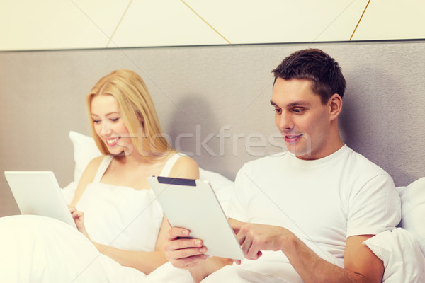smiling couple in bed with tablet pc computers Stock photo © dolgachov