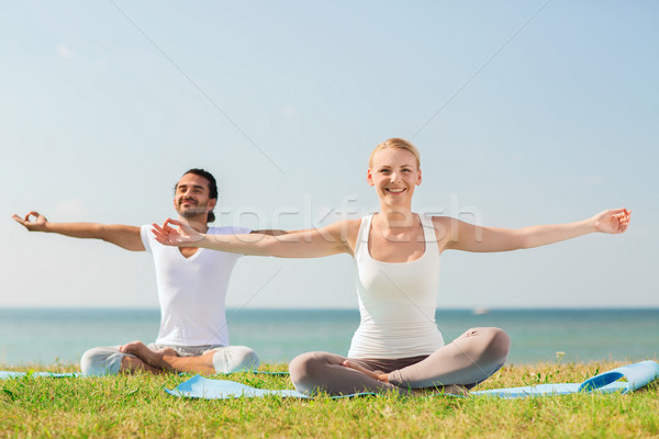 smiling couple making yoga exercises outdoors Stock photo © dolgachov