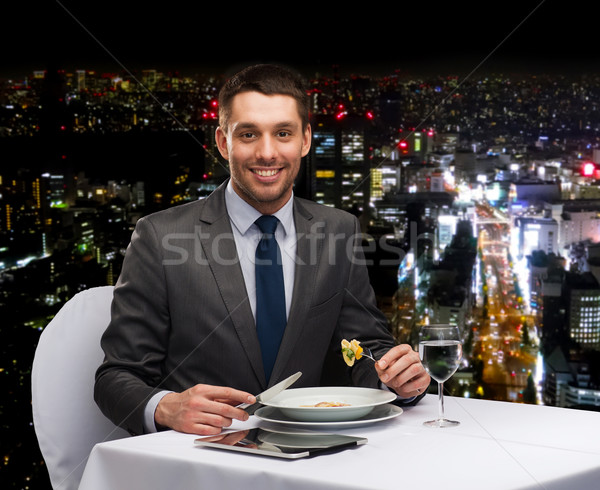 smiling man with tablet pc eating main course Stock photo © dolgachov
