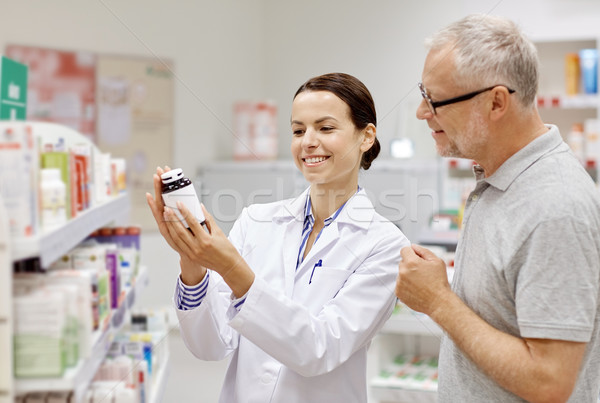 pharmacist showing drug to senior man at pharmacy Stock photo © dolgachov