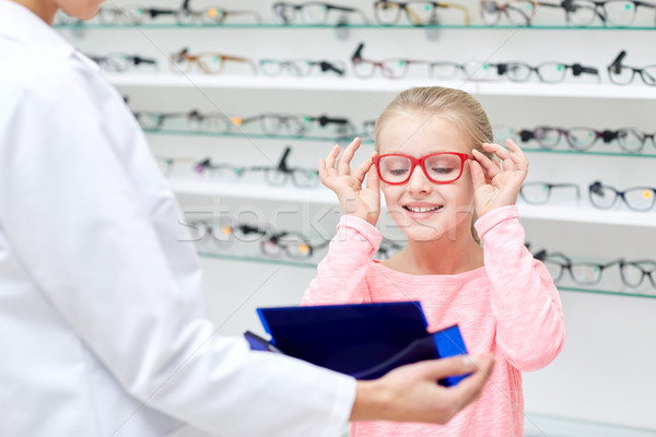 Stock photo: optician and girl choosing glasses at optics store