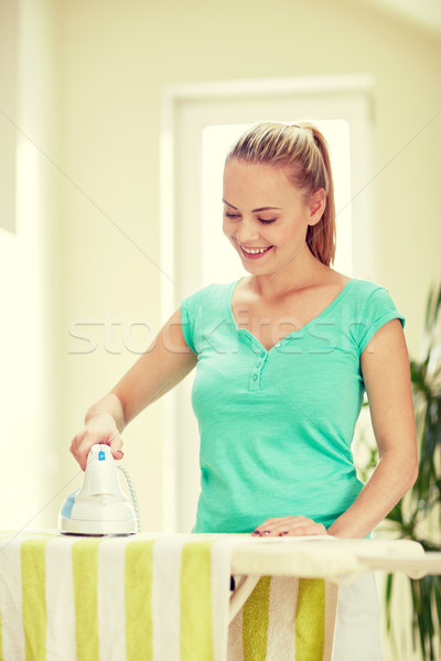 happy woman with iron and ironing board at home Stock photo © dolgachov