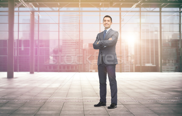 smiling businessman over empty hall and city Stock photo © dolgachov
