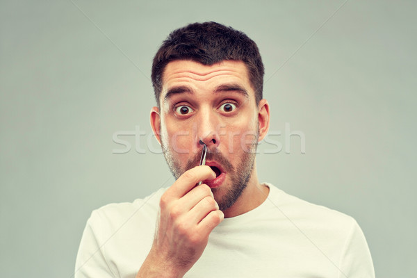 Stock photo: man with tweezers tweezing hair from nose