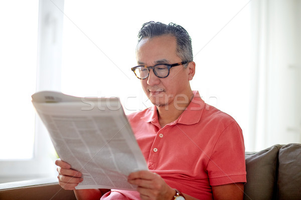 Stock photo: happy man in glasses reading newspaper at home