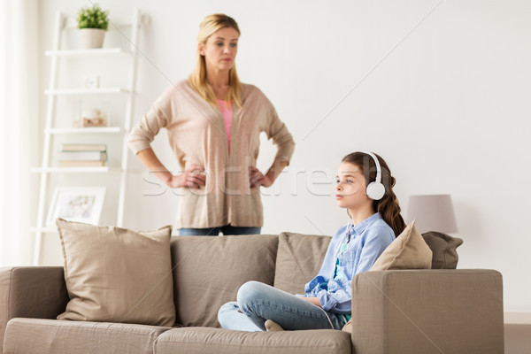 girl with earphones and angry mother at home Stock photo © dolgachov