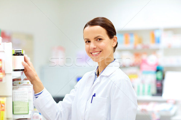 happy female apothecary with drug at pharmacy Stock photo © dolgachov
