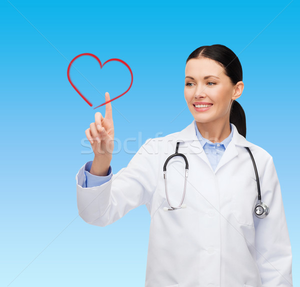 smiling female doctor pointing to heart Stock photo © dolgachov