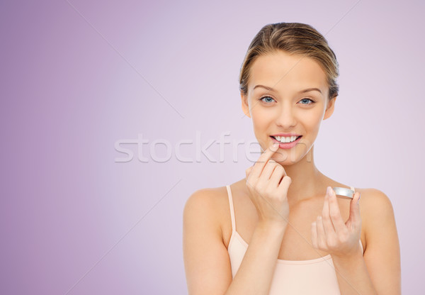 smiling young woman applying lip balm to her lips Stock photo © dolgachov