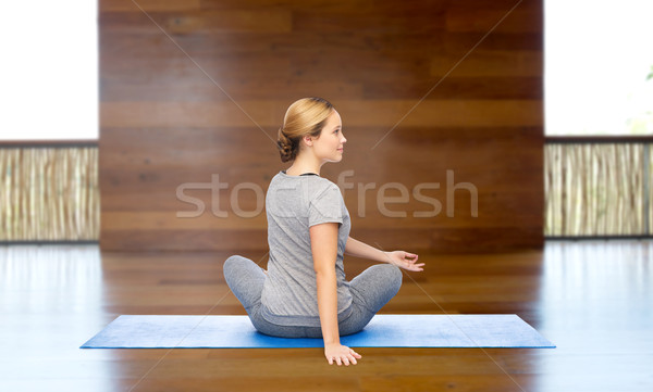 woman making yoga in twist pose on mat Stock photo © dolgachov