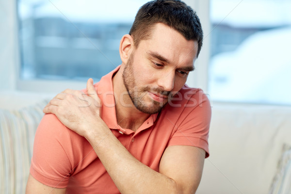 unhappy man suffering from neck pain at home Stock photo © dolgachov