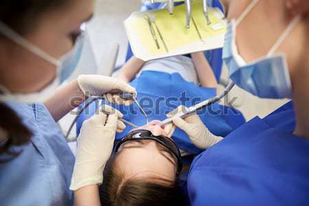 female dentist treating male patient teeth Stock photo © dolgachov