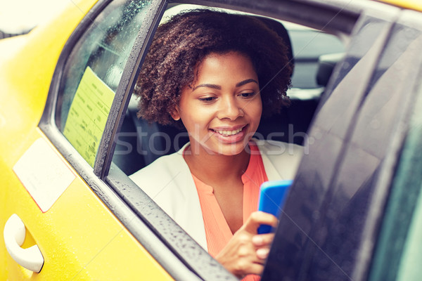 happy african woman texing on smartphone in taxi Stock photo © dolgachov