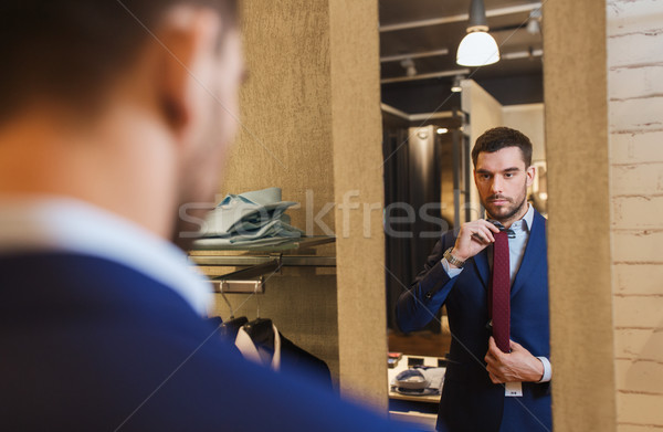 man trying tie on at mirror in clothing store Stock photo © dolgachov