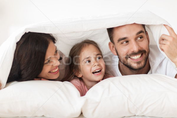 happy family lying in bed under blanket at home Stock photo © dolgachov