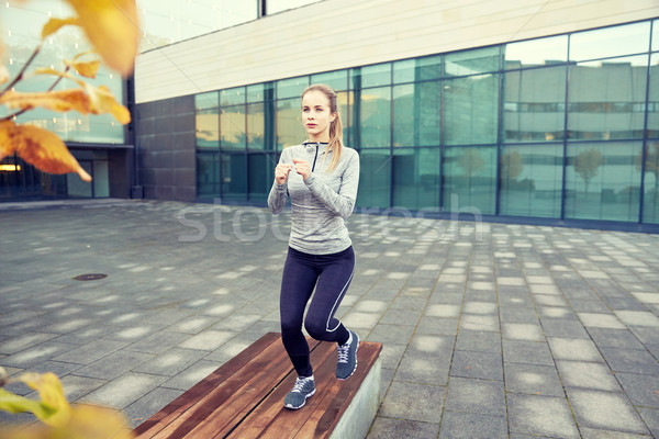 woman making step exercise on city street bench Stock photo © dolgachov