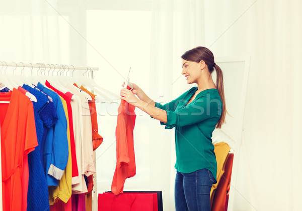 Stock photo: happy woman with shopping bags and clothes at home