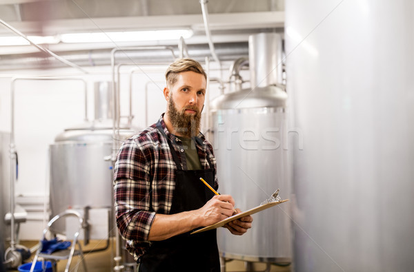 man with clipboard at craft brewery or beer plant Stock photo © dolgachov